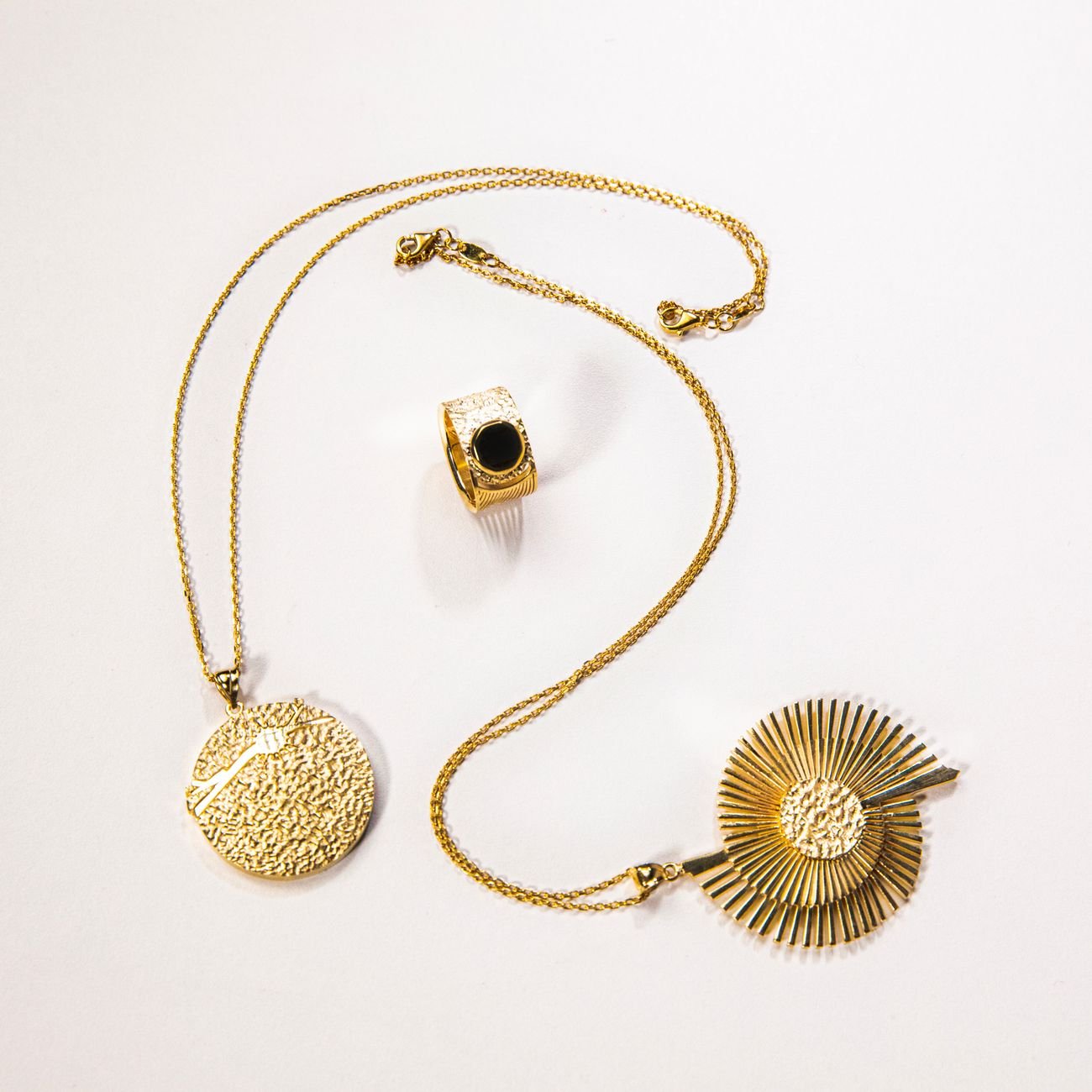 Flat lay of elegant gold necklaces and ring on a white background.