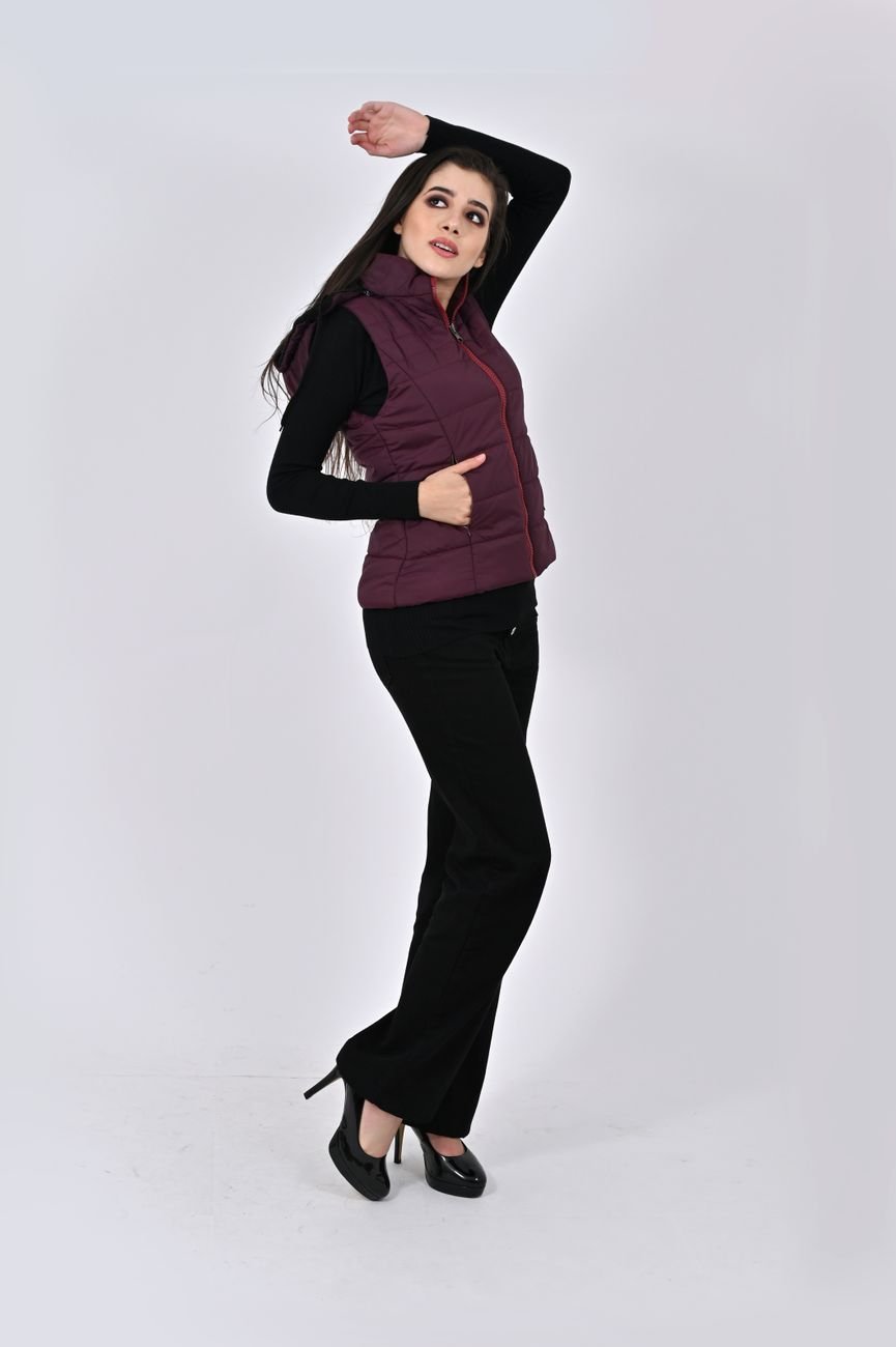 Elegant fashion model posing in a studio wearing a maroon gilet and black outfit.